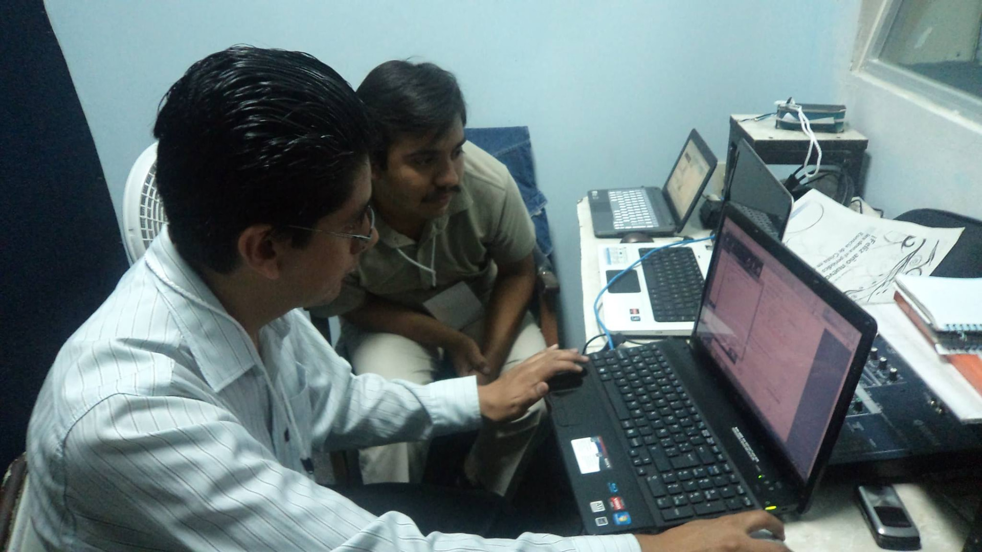 Dos integrantes del equipo preparando una de las primeras transmisiones desde una cabina improvisada
